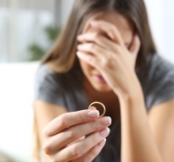 Geschiedene Frau mit Ehering in der Hand