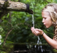 Mdchen trinkt von einem Brunnen (Symbolbild)