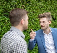 Mann zeigt mit dem Zeigefinger auf anderen Mann.